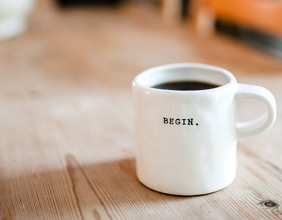 Kaffeetasse mit Aufschrift 'Begin'. Wir hören zu. Website-Erstellung beginnt mit Verständnis.